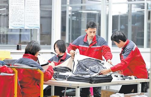 11月14日，安美桥（南宫）羊绒制品有限公司首席质量官赵建军（右二）在检查羊绒围巾质量。本报记者 赵永辉摄