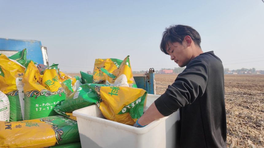 武志强正在为农机添加肥料。潘高占摄