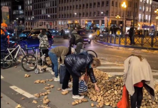 2025年12月18日,在比利时布鲁塞尔,一些市民捡拾示威者遗弃的土豆(视频截图)。新华社发