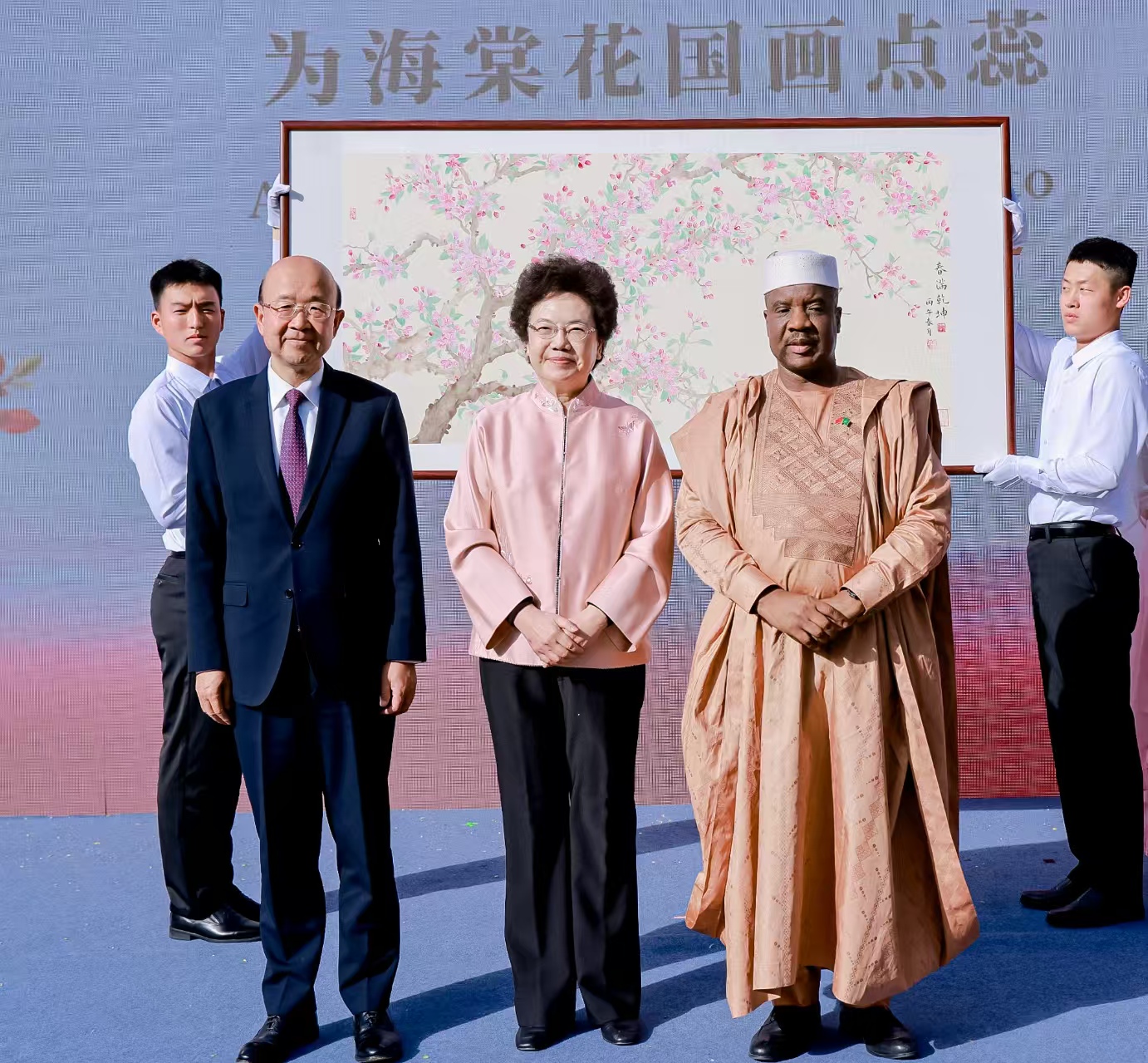 中国宋庆龄基金会主席李斌(中)与中国政府非洲事务特别代表刘显法(左)、非盟驻华代表巴赫(右)一起为此次活动新创作的国画《春满乾坤》上点落花蕊。 中国宋庆龄基金会供图